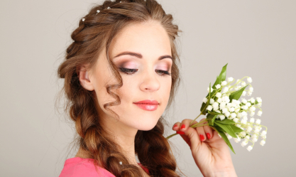 Young woman with beautiful hairstyle and flowers, on grey background