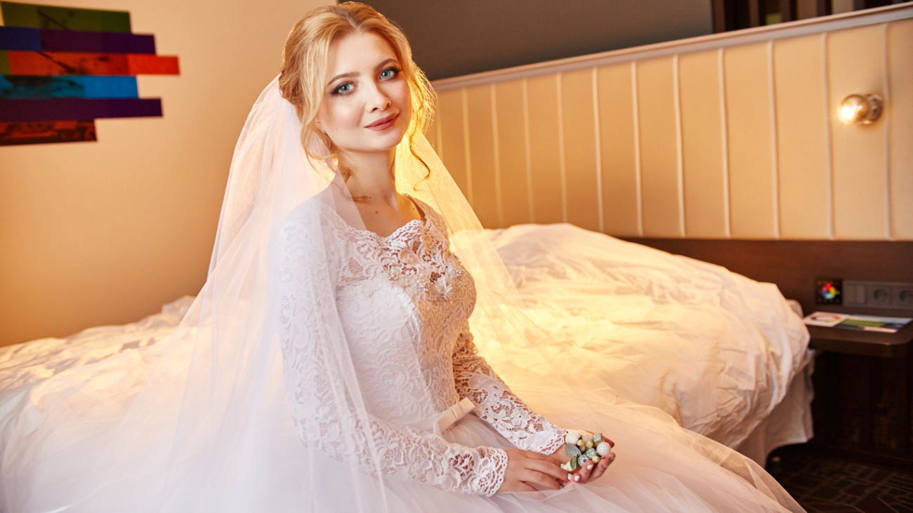 Beautiful bride in white wedding dress on wedding day. A woman is waiting for her fiancé before the wedding ceremony. Girl with a veil on her head