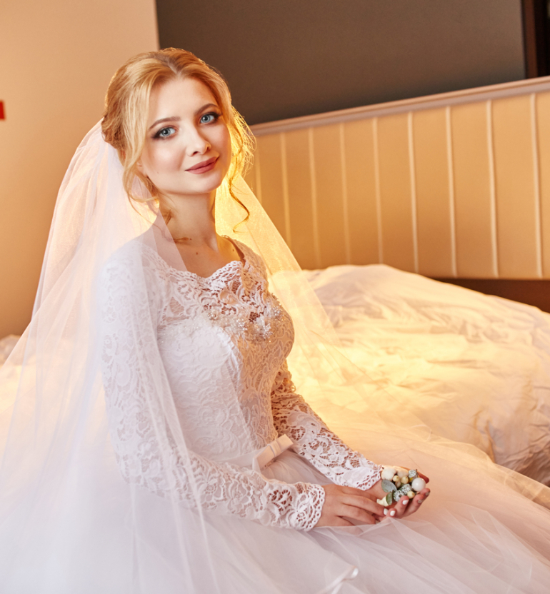 Beautiful bride in white wedding dress on wedding day. A woman is waiting for her fiancé before the wedding ceremony. Girl with a veil on her head