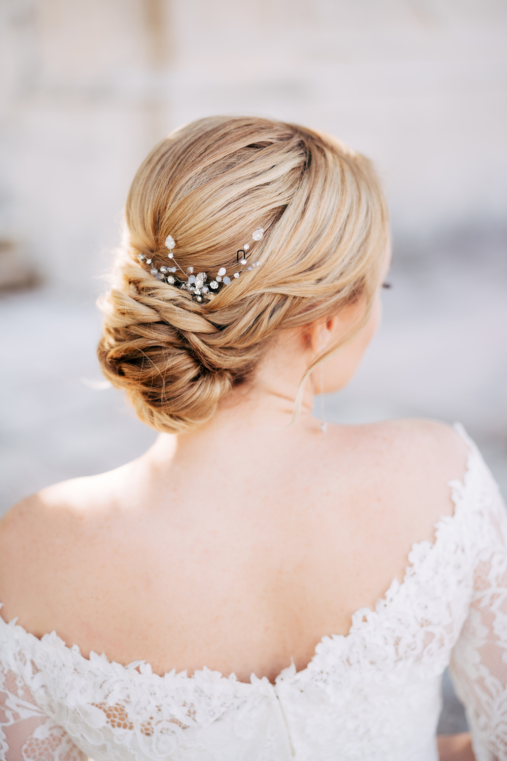 Blonde bride with a beautiful hairstyle and in a dress with bare shoulders, back view . High quality photo