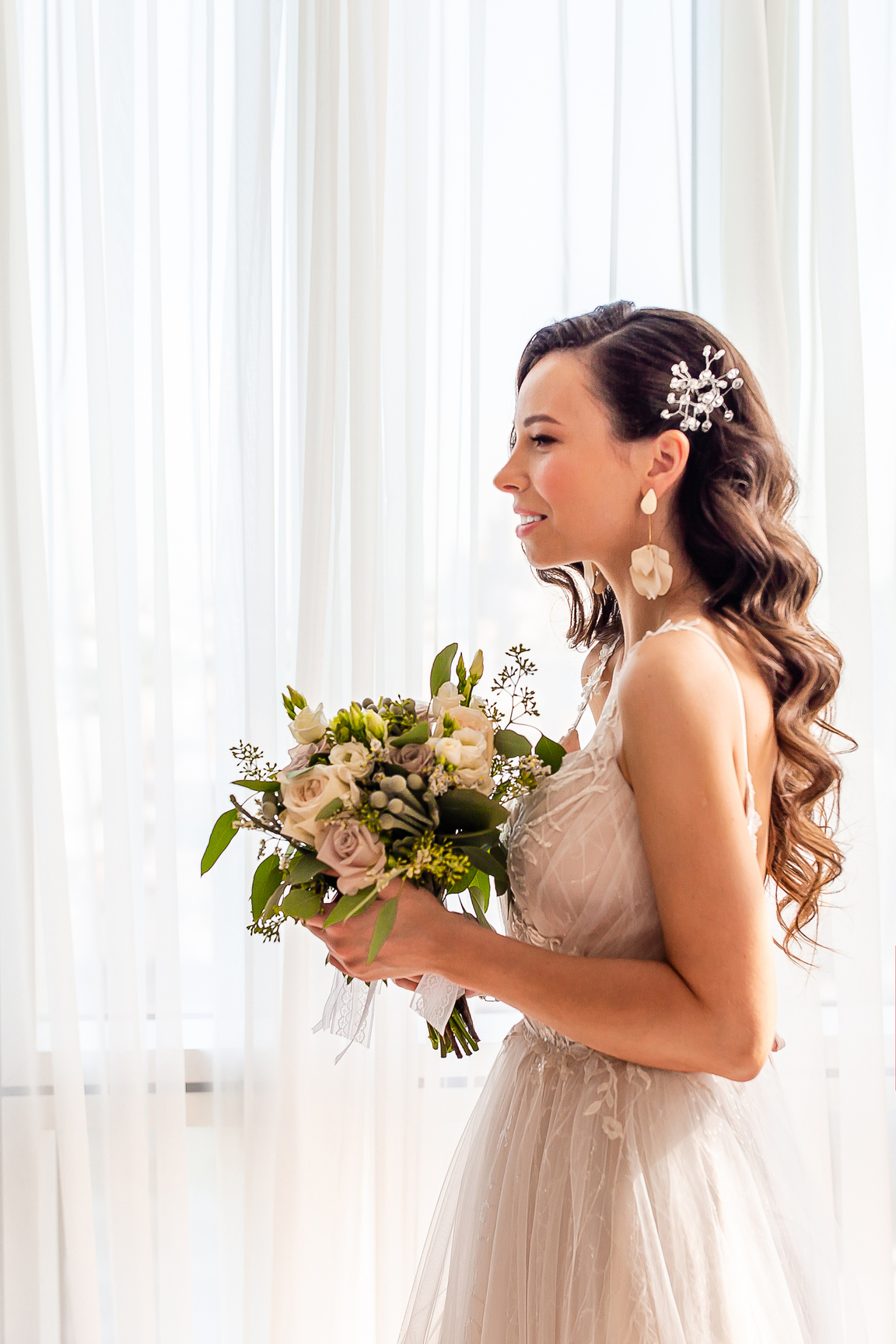 Beautiful bride with wedding flowers bouquet in wedding dress. Bride with wedding makeup and hairstyle in hotel