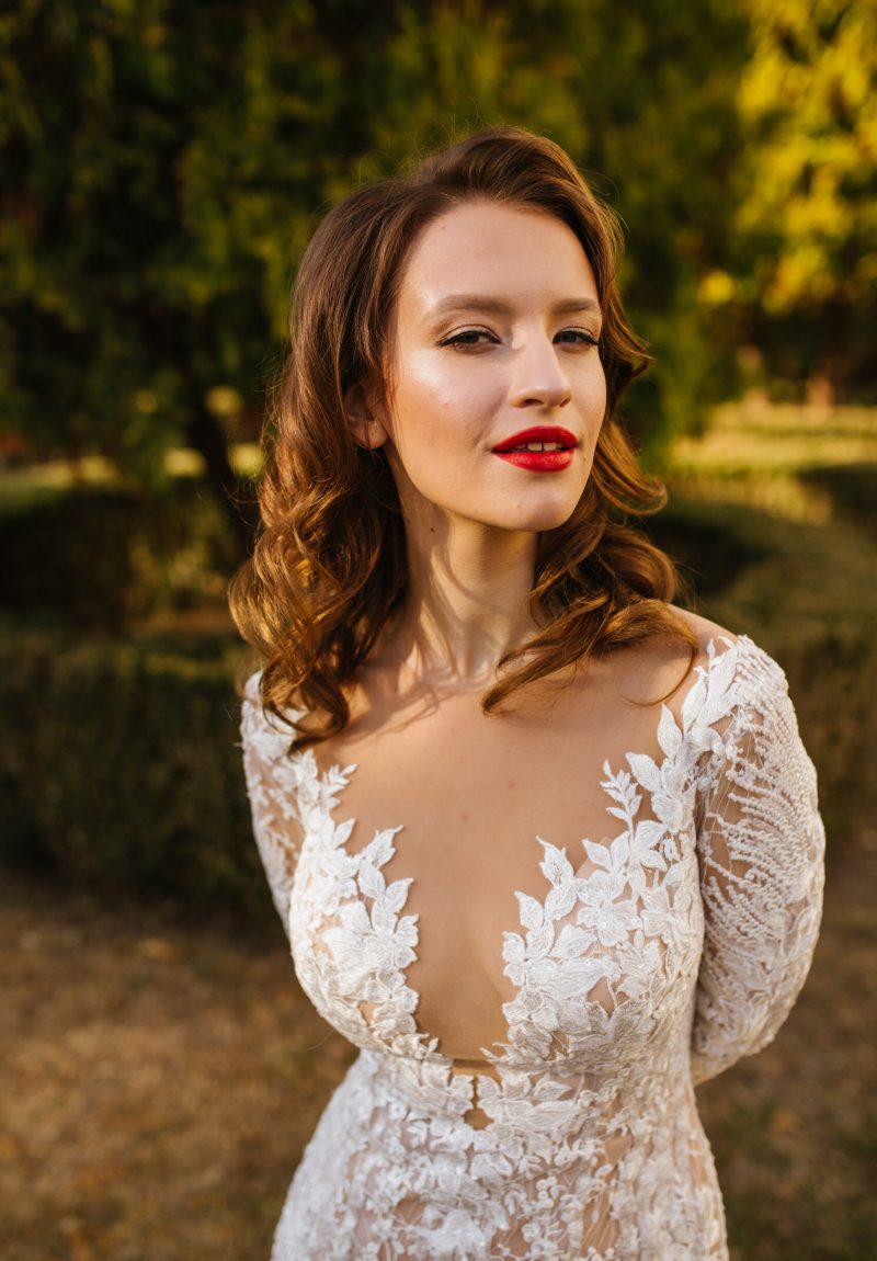 A portrait of a dreamy lady in a wedding dress posing indoor with flowers. Wedding, beauty, fashion.