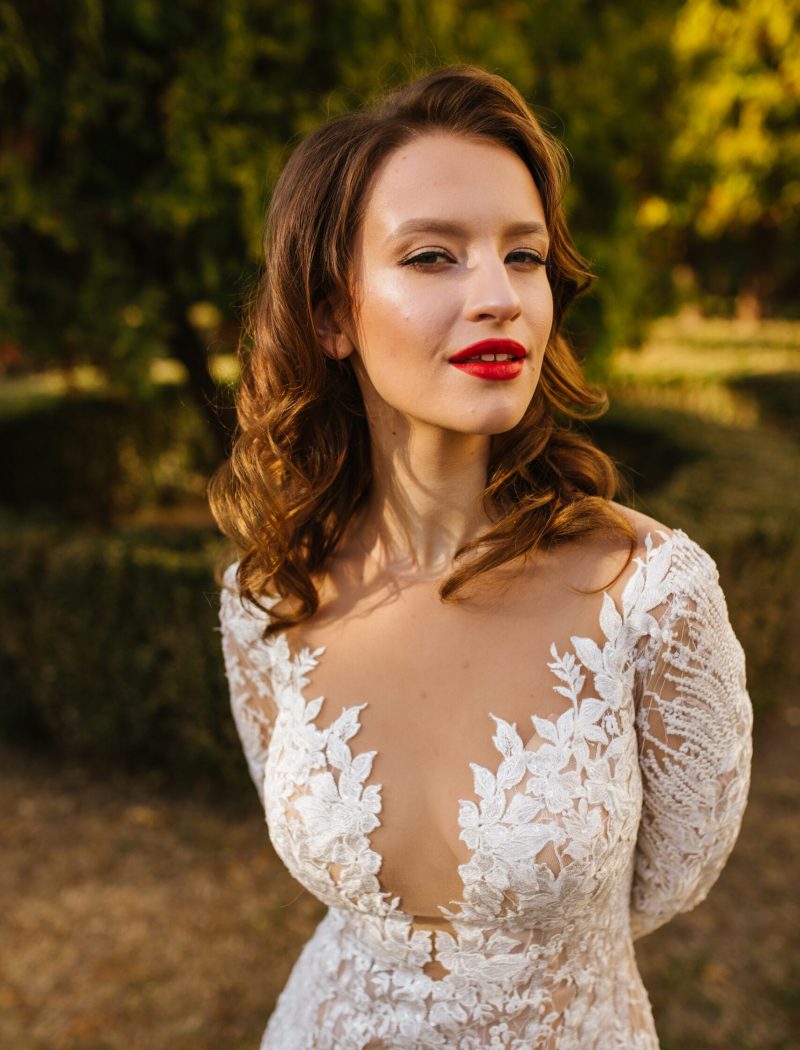 A portrait of a dreamy lady in a wedding dress posing indoor with flowers. Wedding, beauty, fashion.
