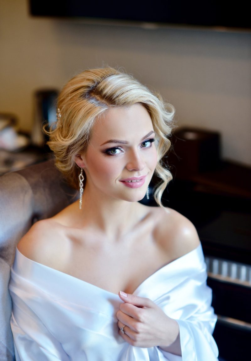 Beauty bride in dressing gown with bridal makeup indoors. Beautiful model girl in colorful wedding robe. Female portrait of cute lady. Woman with hairstyle