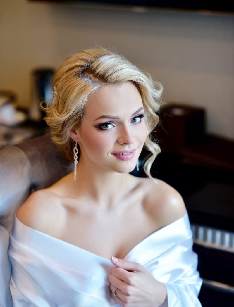 Beauty bride in dressing gown with bridal makeup indoors. Beautiful model girl in colorful wedding robe. Female portrait of cute lady. Woman with hairstyle