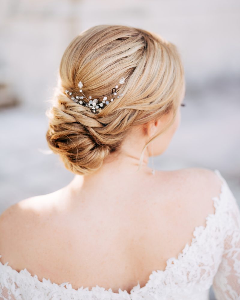 Blonde bride with a beautiful hairstyle and in a dress with bare shoulders, back view . High quality photo